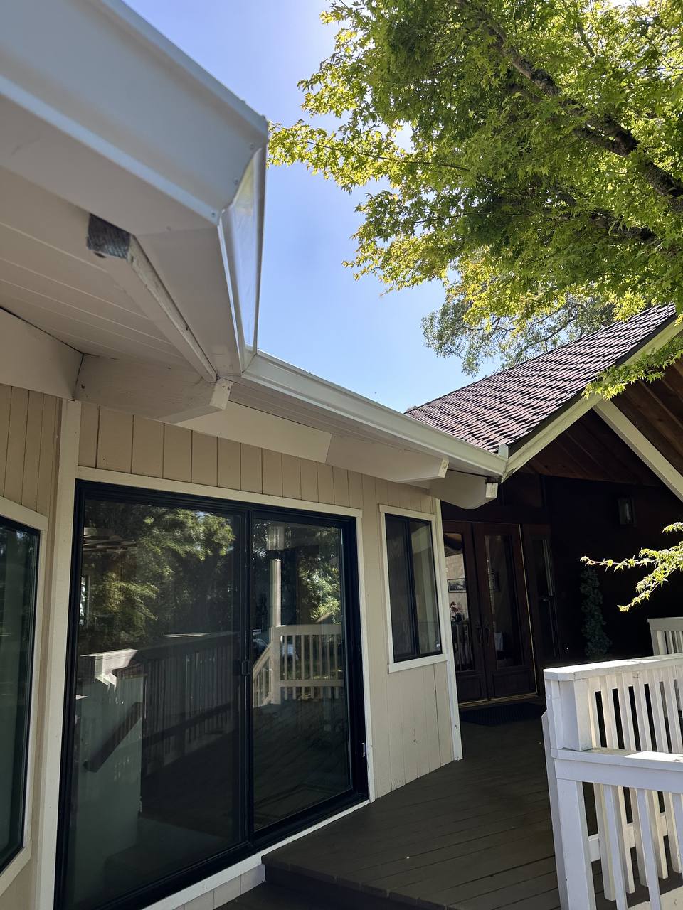 White gutter and fascia installed above a sliding glass door on a covered deck