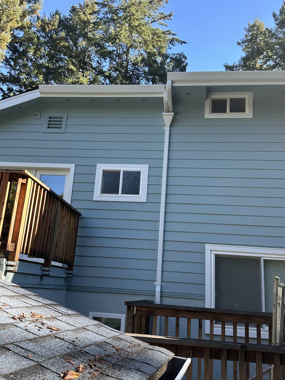 Long seamless gutter and downspout run along the full side of a two-story home