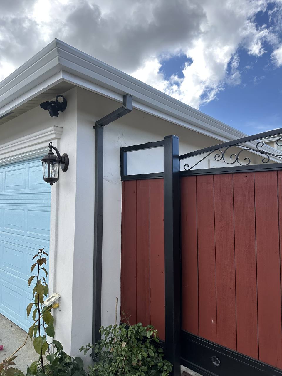 Gutter elbow and mounting bracket installed beside a home's garage