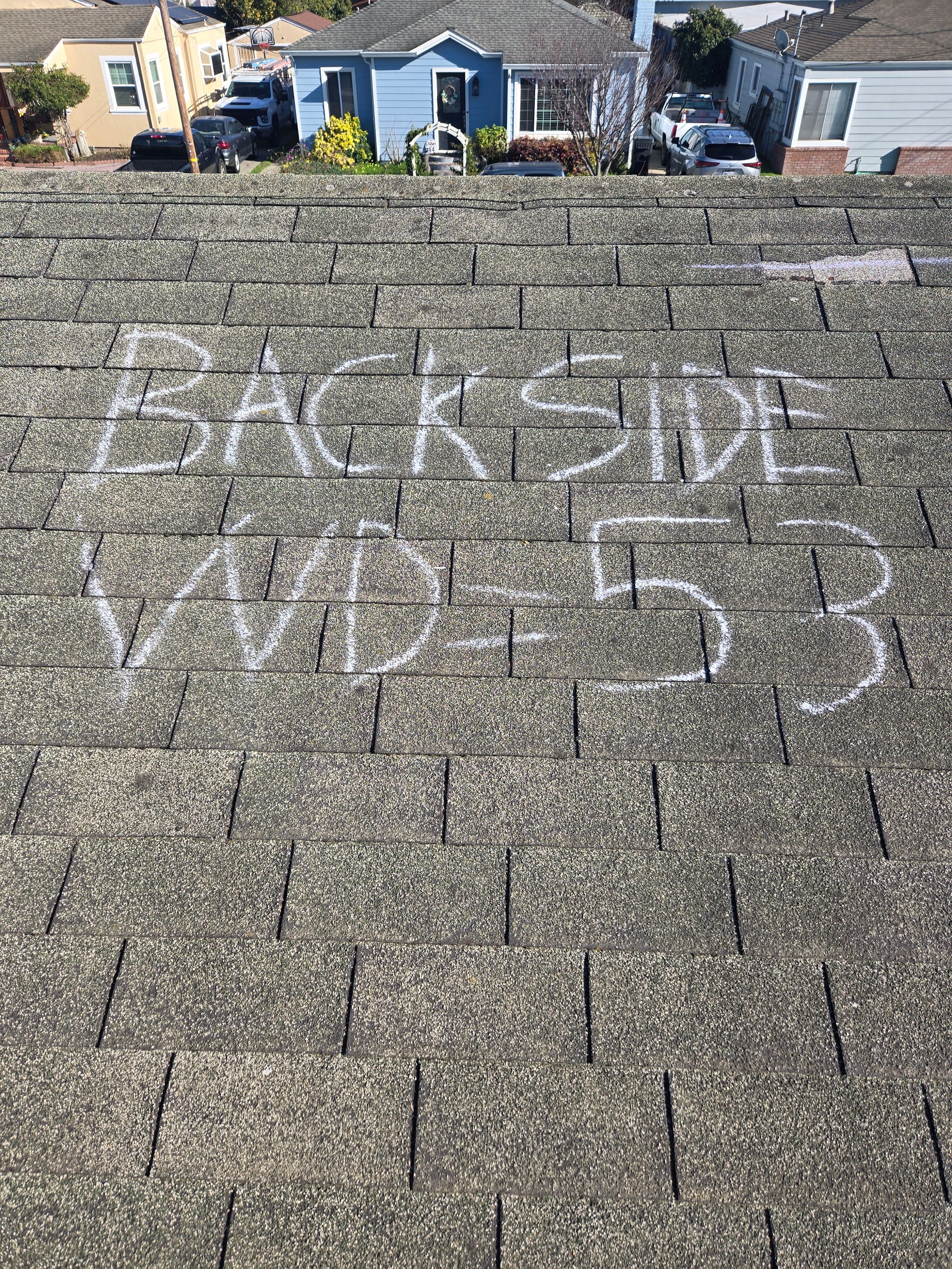 Chalk-marked wind damage labeled Back Side WD-53 documented during an insurance roof inspection