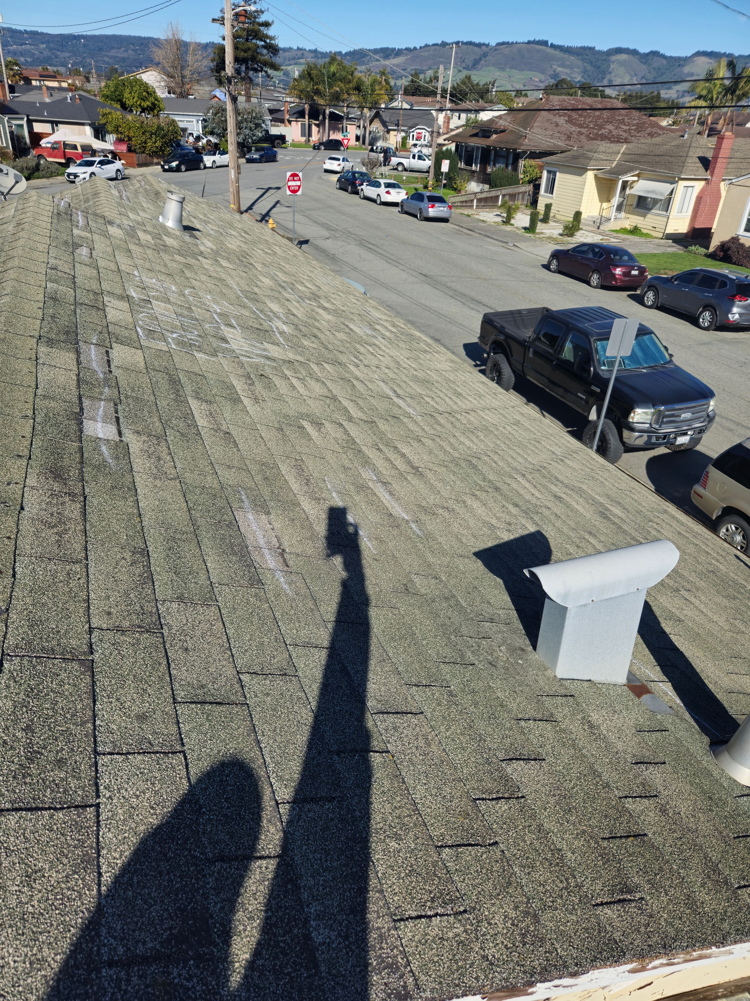 Multiple storm damage marks documented across roof shingle courses for an insurance claim