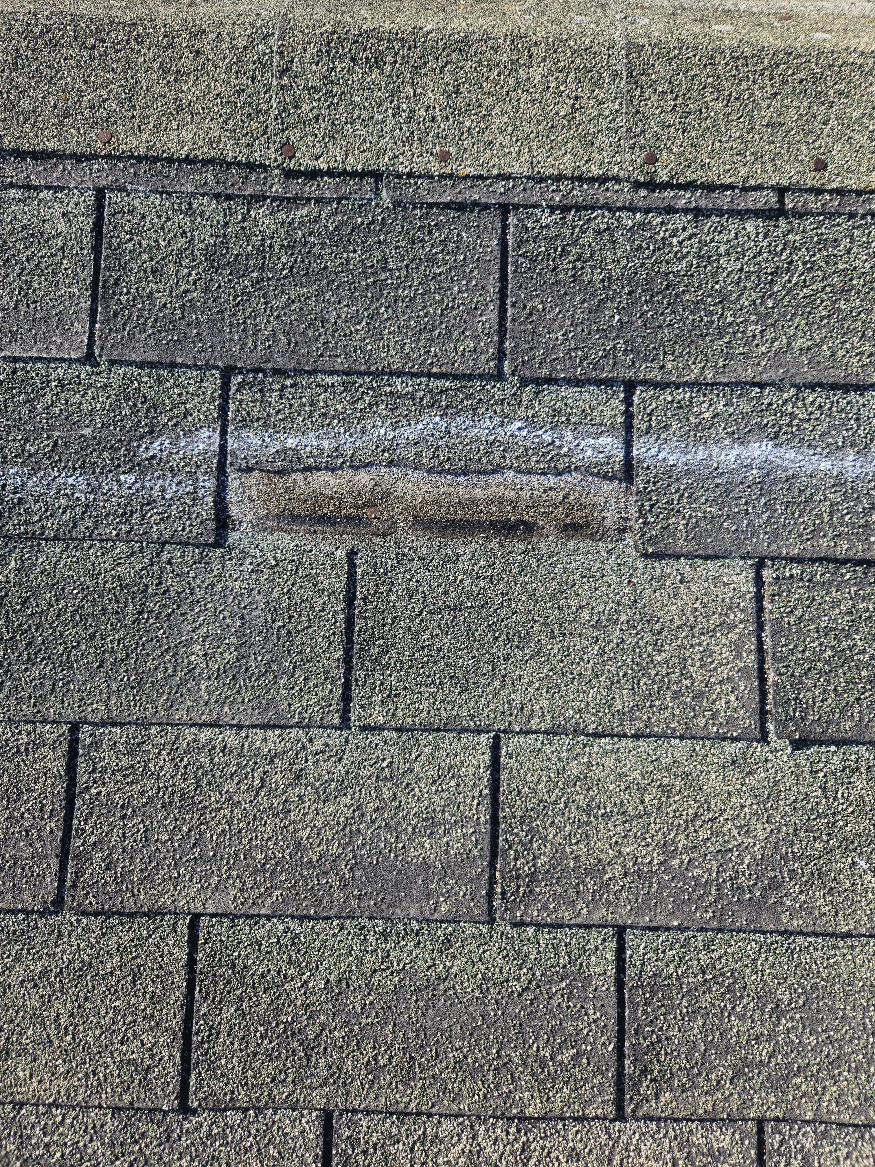 Close-up of storm-damaged shingle marked during insurance claim documentation