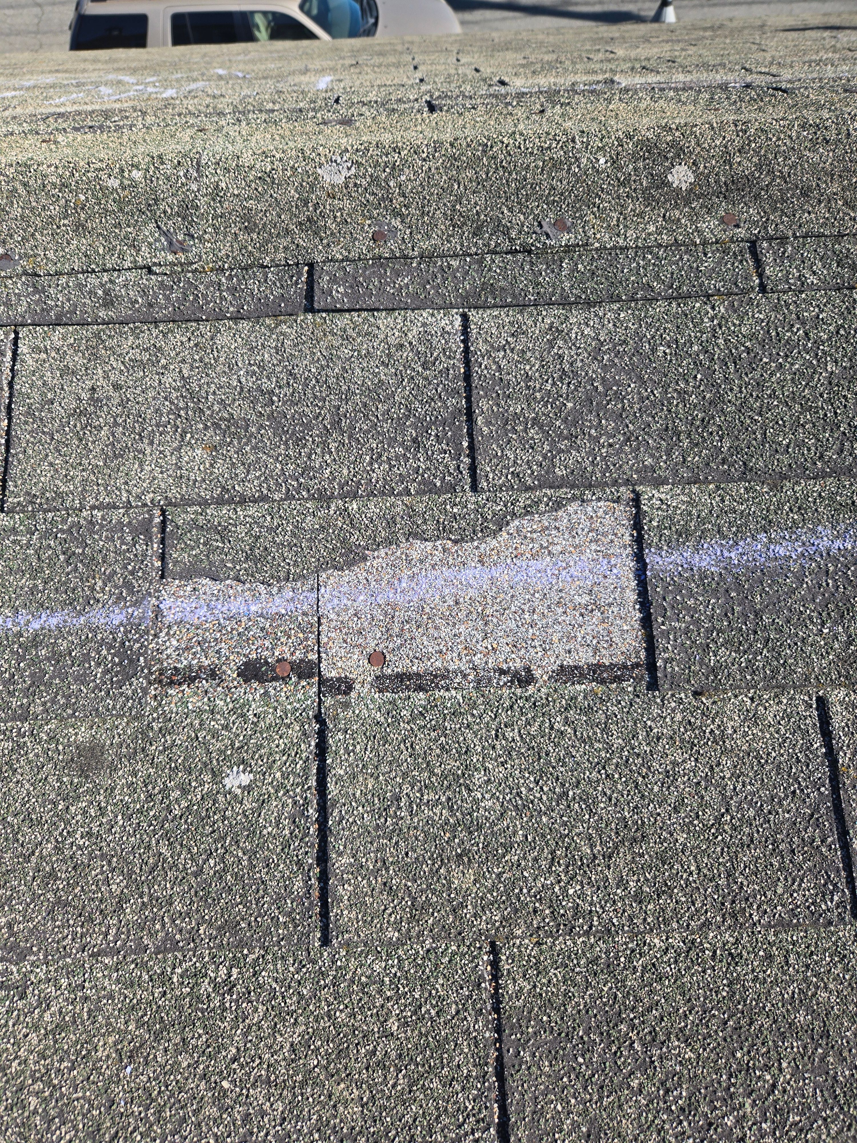 Close-up of wind-damaged shingle marked during an insurance claim inspection