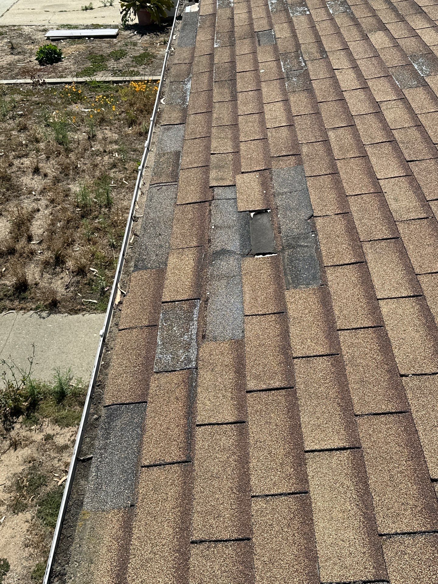 Wind-damaged roof shingles before insurance claim repair