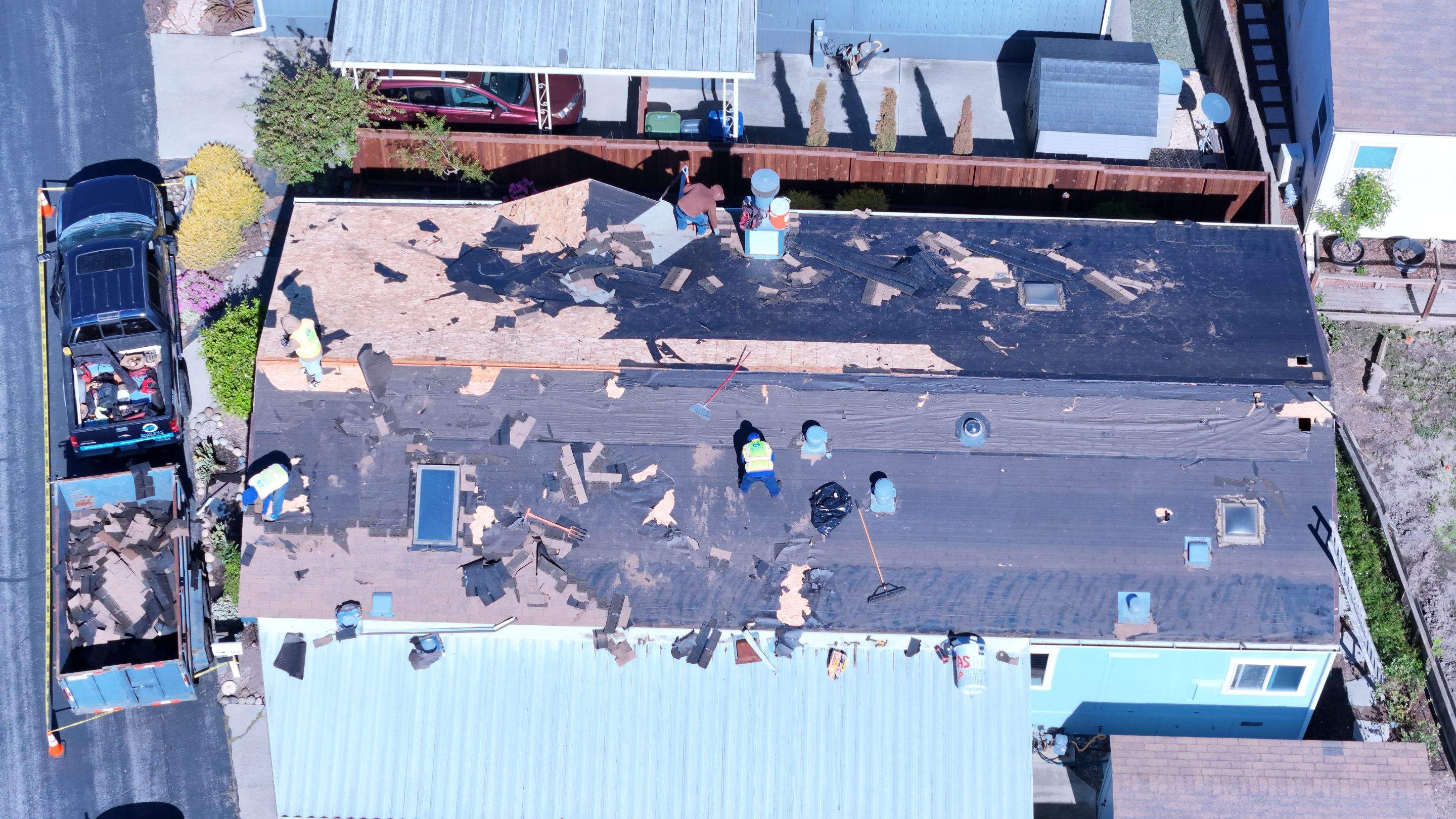 Roofing crew tearing off damaged roof during insurance-approved replacement