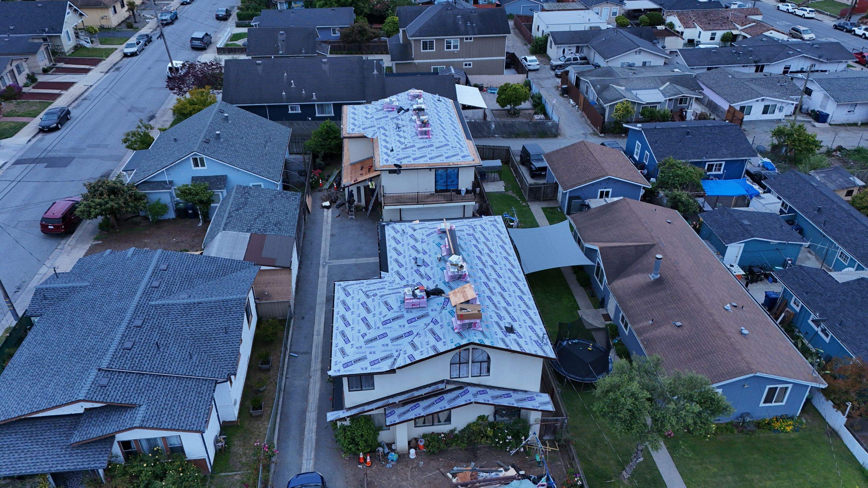 Aerial view of multiple roof installation projects underway in a neighborhood